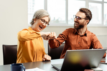 Overjoyed business colleagues bumping fists celebration success while working together