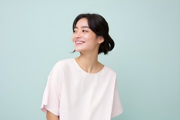 Fototapeta premium Portrait of a joyful fictional Korean woman smiling. Graceful and elegant lady. Natural beauty. Happiness. Isolated on a plain colored pastel background. Generative AI.