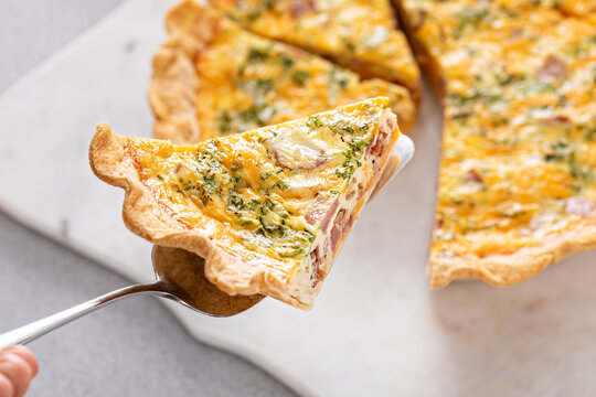 Homemade quiche with ham and cheese cut on the table