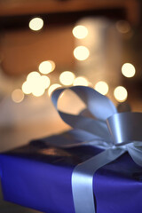 Wrapped present closeup in front of twinkling lights
