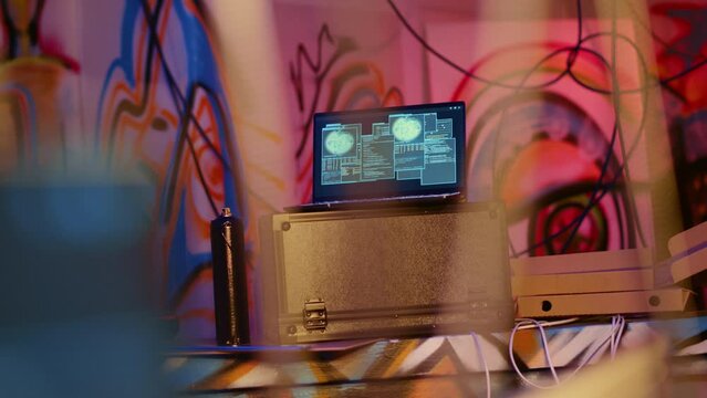 Laptop in underground bunker with graffiti painted walls left behind by hackers to act as decoy, running script pinging wrong location to cybercriminal law enforcement chasing them