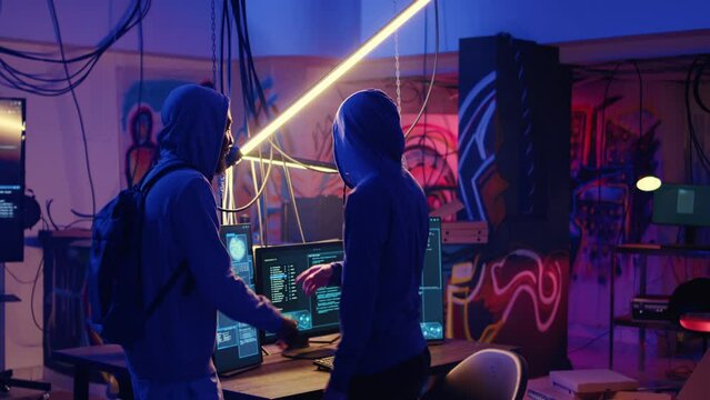 Hooded criminals in ghetto underground place discussing ways to evade getting caught by police after stealing data from victims using malware, brainstorming ways to hide their online activity