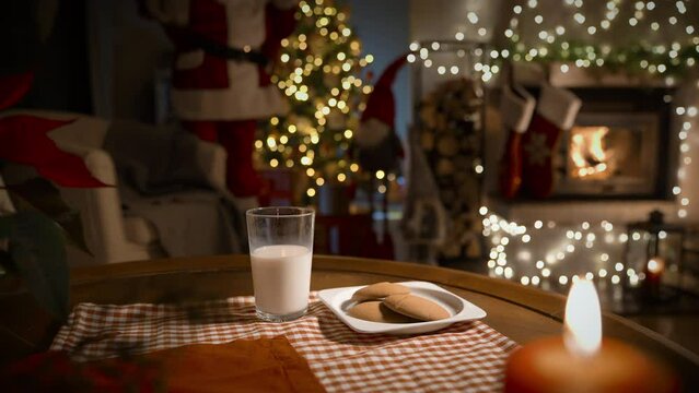 Santa Claus bringing gifts, eating ginger cookies and drinking milk on Christmas night in the decorated living room with fireplace and Christmas tree