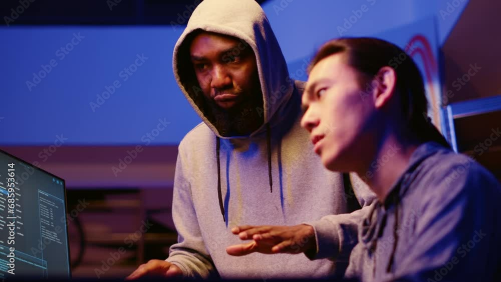 Poster bipoc hackers in dimly lit room discussing ways to breach defenses and exploit weaknesses in pc syst