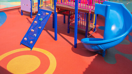 Colorful jungle gym with slide and playground equipment on rubber tile floor in outdoors playground...
