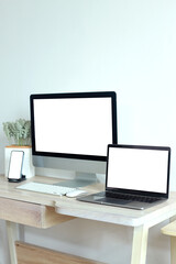 Mockup of laptop computer and mobile phone with white blank screen on office table 