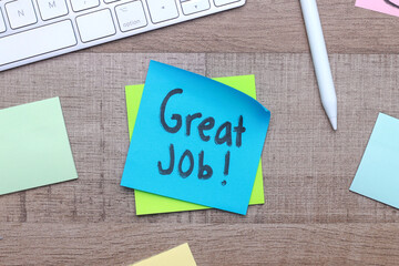 Great Job text on sticky notes with office stationery over wooden background