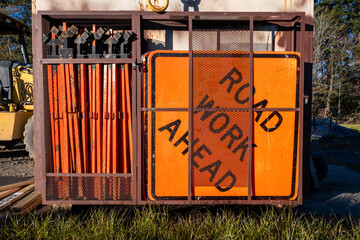 Construction supply trailer with stack of Road Work Ahead bright orange signs for traffic...