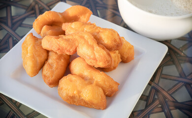 Deep fried dough stick or Youtiao, Chinese fried breadstick, serving on white plate. Popular food...