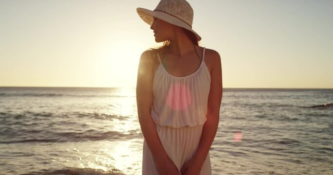 Woman, happy and beach in sunset, summer and enjoy the ocean, nature and seaside. Travel, holiday and smile for vacation, calm and peaceful with freedom, lens flare and outdoor to relax, hat and trip