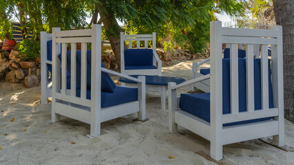 Recreation area on the beach. White wooden chairs with soft blue cushions stand around a round...