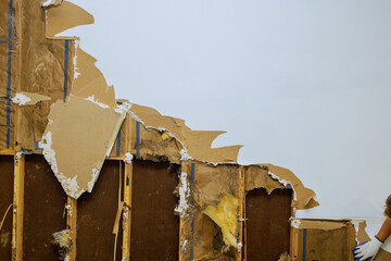 Dismantling old damaged plasterboard drywall during reconstruction of house