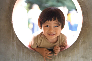 公園の遊具の窓から覗く子供/Child looking through the window of a playground equipment...