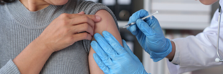 Asian woman receives flu vaccine at hospital Hands of a male doctor or professional nurse in...