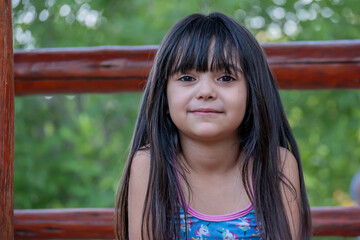Portrait of a cute Argentinian girl with long hair, who plays in the park.