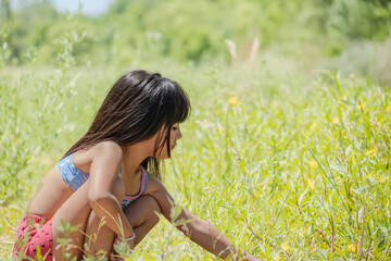 Little girl playing with the flowers growing in the meadow.