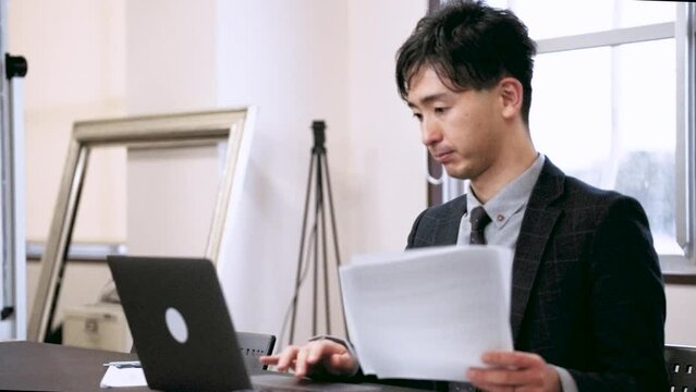 ノートパソコンを使って資料を作成する男性ビジネスマン