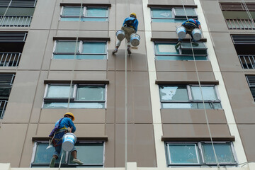 A painter is abseiling from a high-rise building. A painter using sling cables and safety tools. 