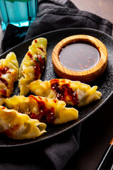 Asian dumplings with hot sauce on the dark background close up vertical photo