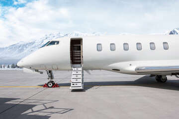 Close-up of the front of the luxury white corporate aircraft with an opened gangway door at the...