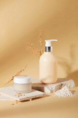 Fototapeta na wymiar Front view of a jar of lotion and a bottle of shower gel are placed on a podium with rice bran powder on a beige background. Skin care with natural ingredients.