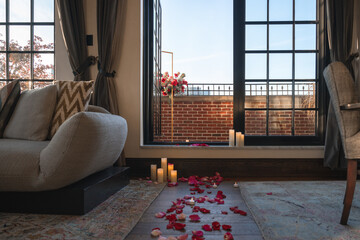 Rose petals and lit candles on the floor lead to a romantic set up out on the red brick terrace. - obrazy, fototapety, plakaty
