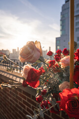 A bouquet of pink and red roses is backlit by the bright sun in the background.