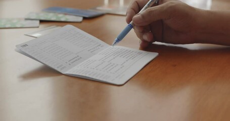 Hands opening bank book to check balance on wooden table
