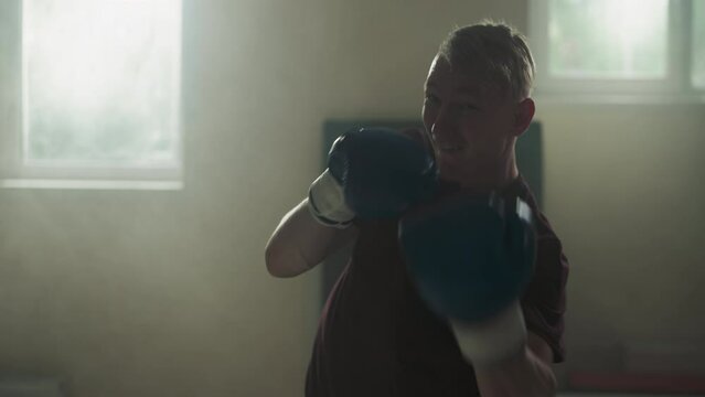 Sportsman does hooks and uppercuts training in sports club. Serious boxer performs punches to camera in gym slow motion. Fighting workout duration