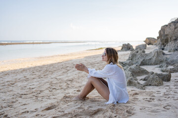 Fototapeta na wymiar Young woman sitting on the beach alone, relax and enjoy nature