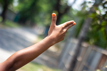 A man has two finger on his hand pointing forward and the thumb pointing up and the background blur