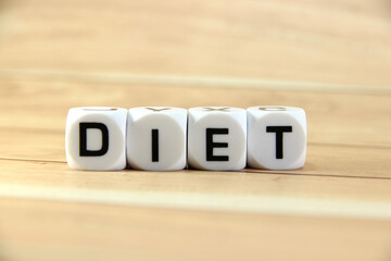 "DIET" text or message short word english letter on white block with brown wood pantern background.
