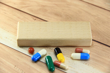 Empty wooden block for text or message short word english letter with capsule pills on brown wood...