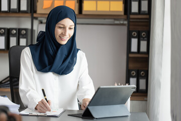 Happy muslim woman working at desk in office, 