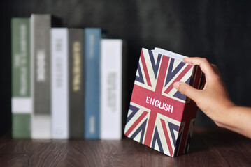English book with hand selected from the bookshelf. Learning English fluently are benefits for...
