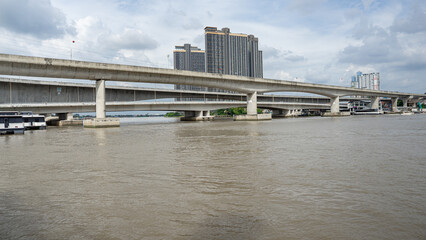 Image of a large river flowing through the suburbs. The picture was taken from the river bank on the left. Go to the right where there are commercial buildings and residences in the area.