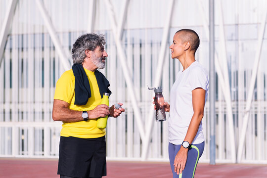 senior man talking to his personal trainer before training, concept of healthy and active lifestyle in middle age