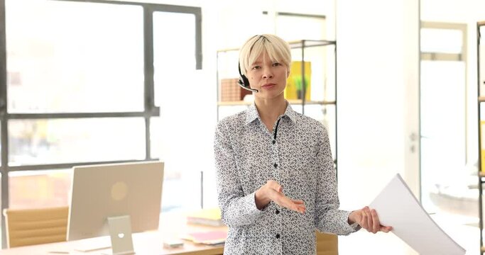 Businesswoman in headphones with microphone talking remotely in office 4k movie. Freelance and online business seminars concept