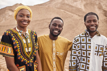 Group of young African American people wearing traditional clothing in desert, all smiling