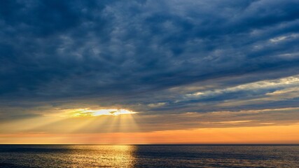 The rays of the sun shine through the clouds. Colorful cloudy sky at sunset. Gradient color. Sky texture, abstract nature background. Positive photography.