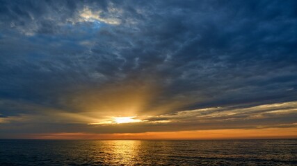 The rays of the sun shine through the clouds. Colorful cloudy sky at sunset. Gradient color. Sky texture, abstract nature background. Positive photography.