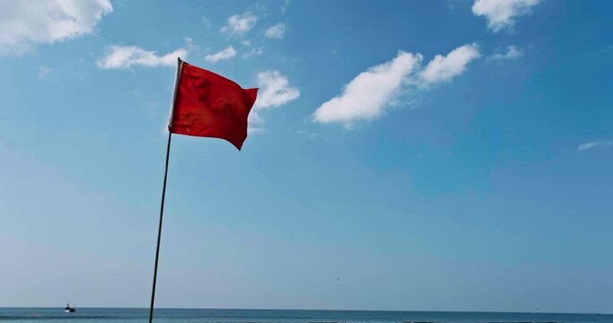 red flag on beach on sea or ocean as symbol of danger. The sea state is considered dangerous and swimming is prohibited.