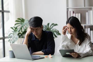 Two young asian businessman and woman are sitting stressed out with work in the office.