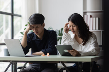 Two young asian businessman and woman are sitting stressed out with work in the office.