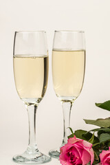 Glasses with sparkling wine on a white background Banner design. Champagne and roses celebrating the holiday