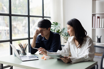 Obraz premium Two young asian businessman and woman are sitting stressed out with work in the office.