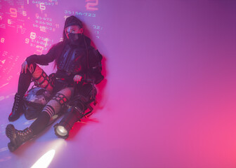A woman in a futuristic tactical black suit lies on the floor, with a motorcycle helmet and a...