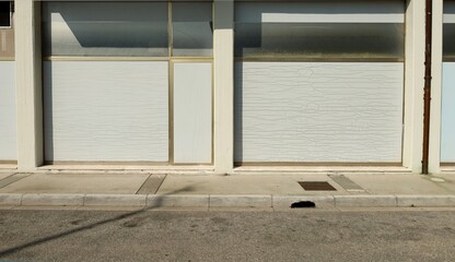 Old abandoned shop with white washed store windows at the road side. Concrete sidewalk and street in front. Background for copy space.