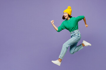 Full body side profile view young woman she in green sweater yellow hat casual clothes jump high...