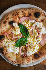 Top view of an authentic italian pizza. It has mozzarella, burrata , mortadella and pistachios.